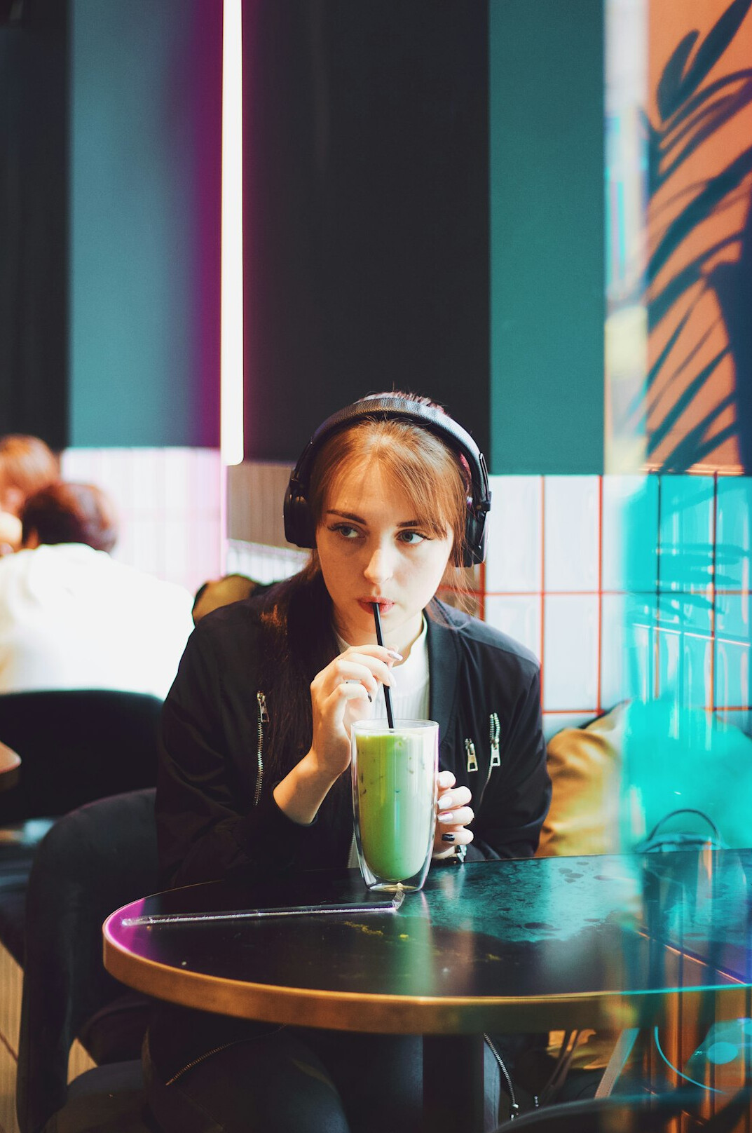 Young woman studying with a tablet and headphones in a cafe